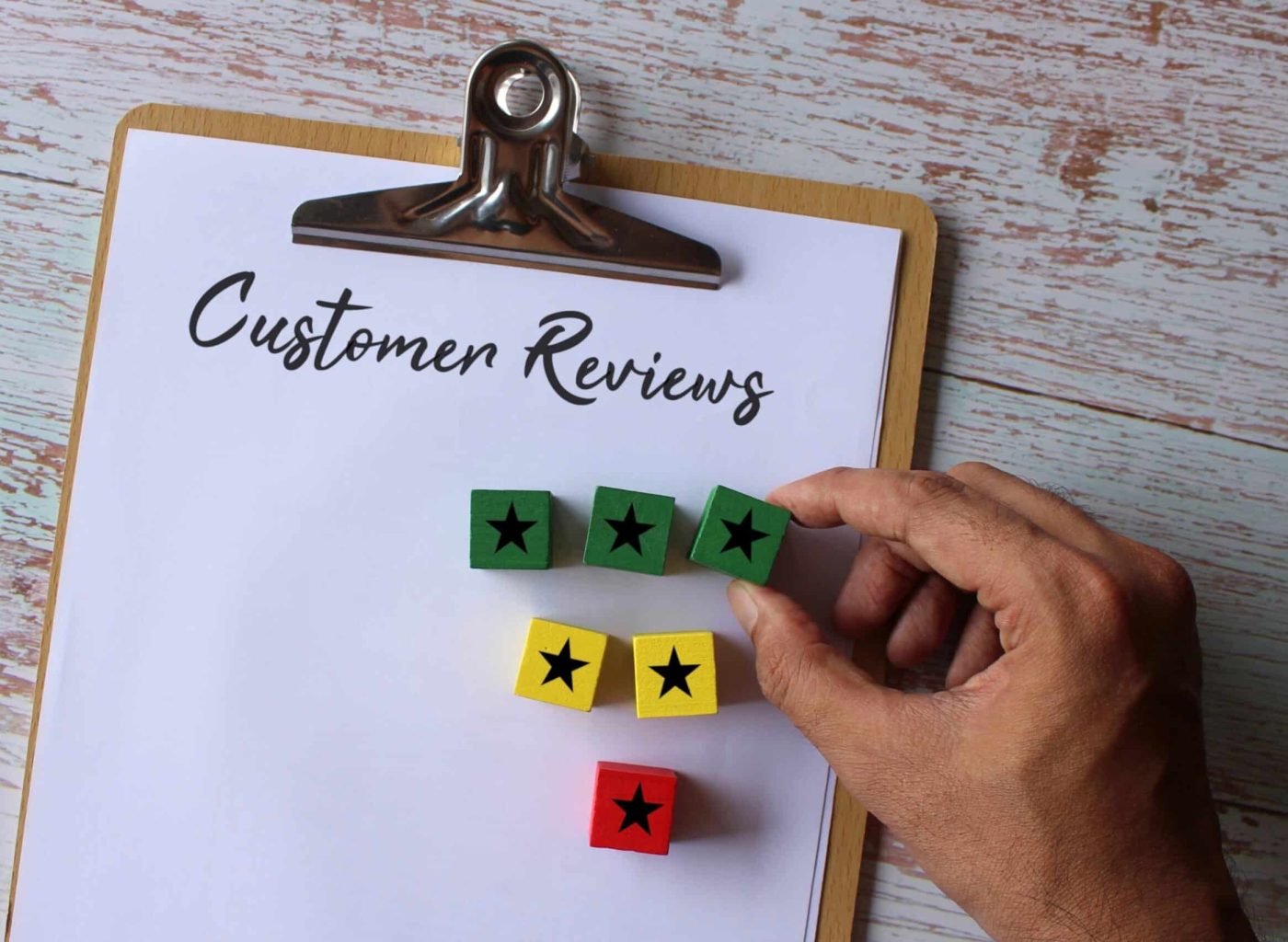 Paper clipboard with text Customer Reviews and wooden cube with star icon. Business concept.